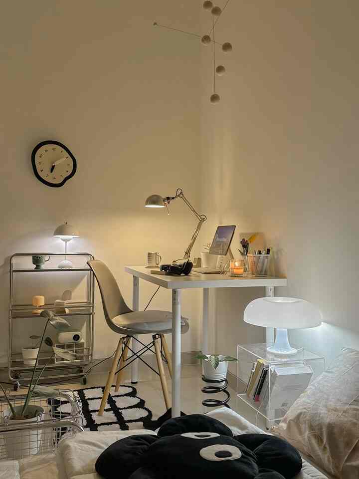 White and beige toned bedroom featuring a modern desk, lamps, and a cozy home office and relaxation space