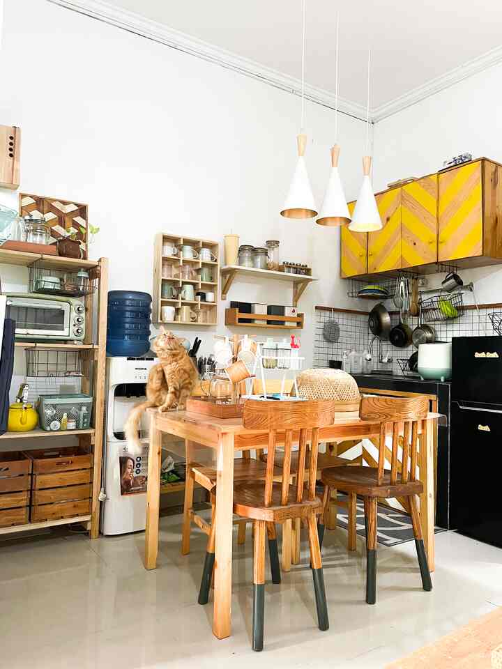 White walls and wood-tone furniture harmonize in a dining room with yellow kitchen cabinets and a cat, creating a warm atmosphere