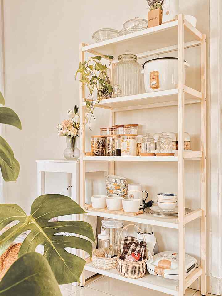 Bright white and wood tone kitchen shelving area featuring organized storage and natural plants
