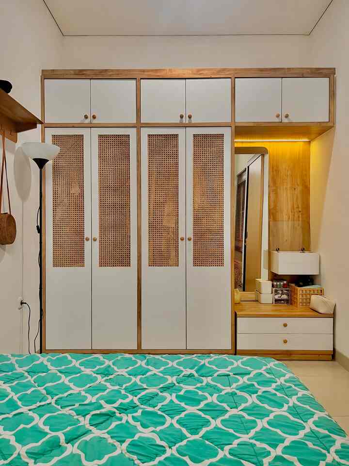 Natural wood tone bedroom featuring large wardrobe and illuminated nightstand creating a cozy atmosphere