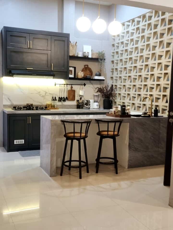 Modern classic kitchen with dark gray and gold accents, featuring a central kitchen island with bar stools in a sleek space