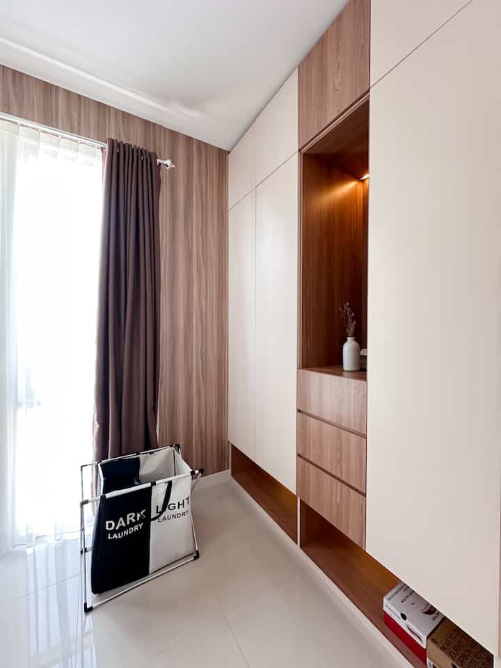 Modern walk-in closet space with natural wood tones and white colors, featuring built-in wardrobes and brown curtains in a cozy interior