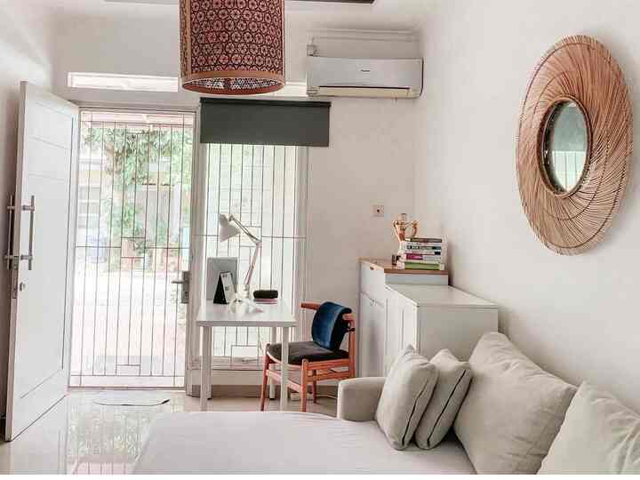White and brown toned living room featuring a simple modern sofa bed, desk, and chair arranged in a cozy space