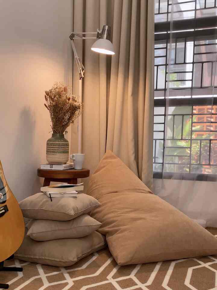 Beige-toned living room reading corner featuring a large beige bean bag, cushions, and a floor lamp creating a warm atmosphere
