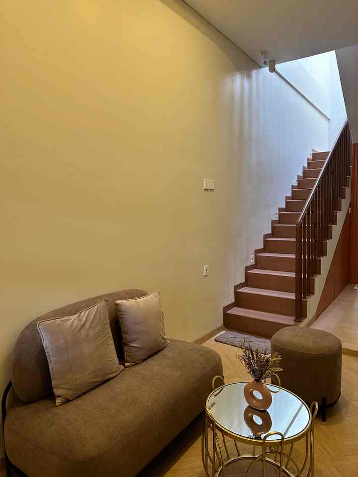 Natural color toned living room featuring brown sofa and round gold coffee table with a simple, warm atmosphere