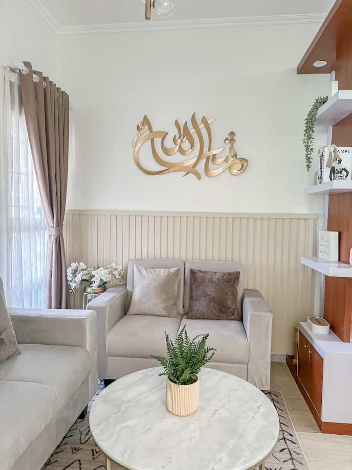 Light beige and white toned living room featuring sofas and round coffee table centered, gold wall decor and natural elements creating a clean space