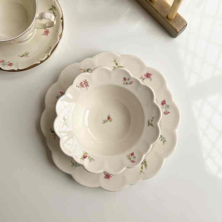 Bright white-tone kitchen table featuring a vintage plate, bowl, and teacup set arranged neatly