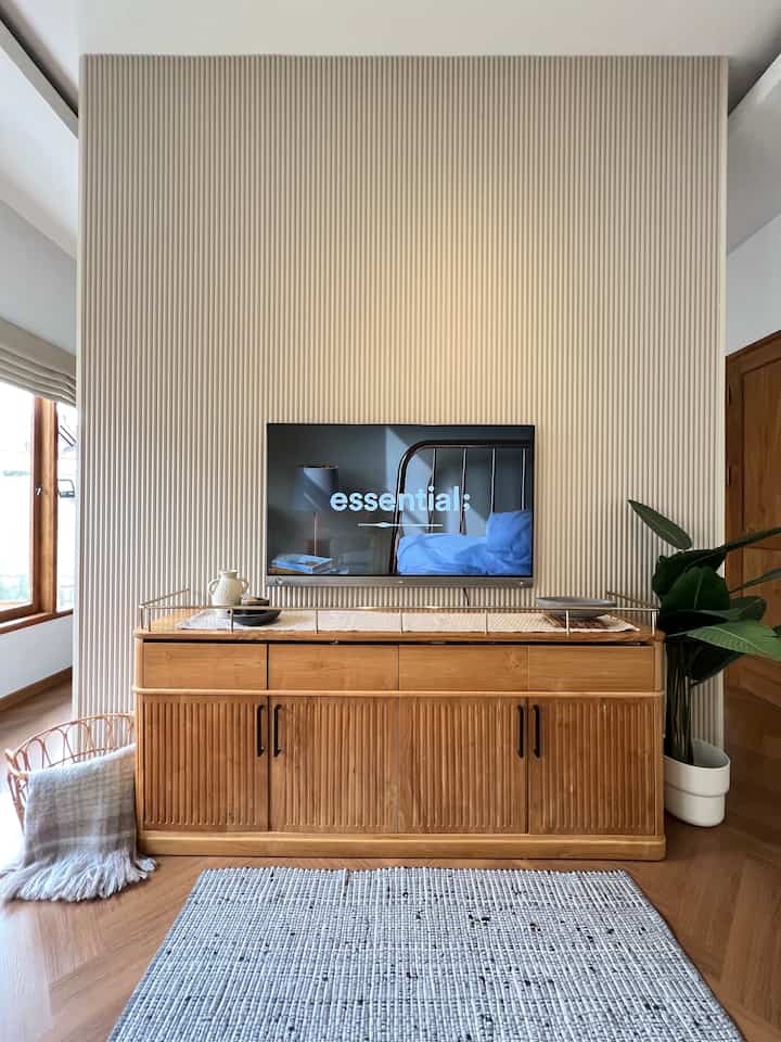 Light brown wood tones and beige wall panel create a harmonious bedroom TV wall area