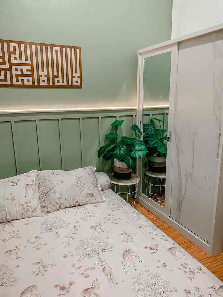 A 3x2.5 meter bedroom with green walls and white wardrobe, featuring floral bedding and a potted plant for a cozy ambiance