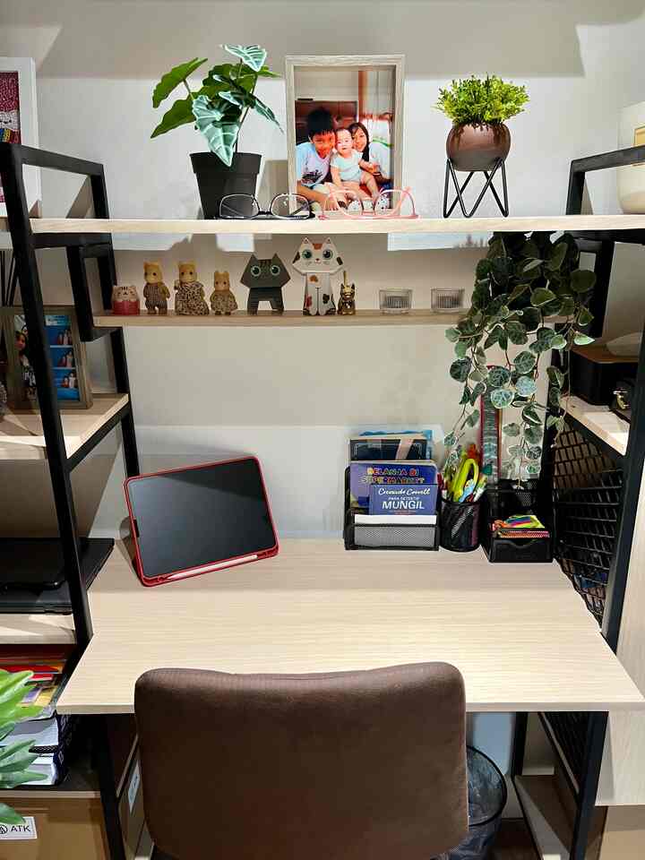 Bright white walls and natural wood-toned home office space featuring a desk, chair, plants, and family photo creating a cozy atmosphere