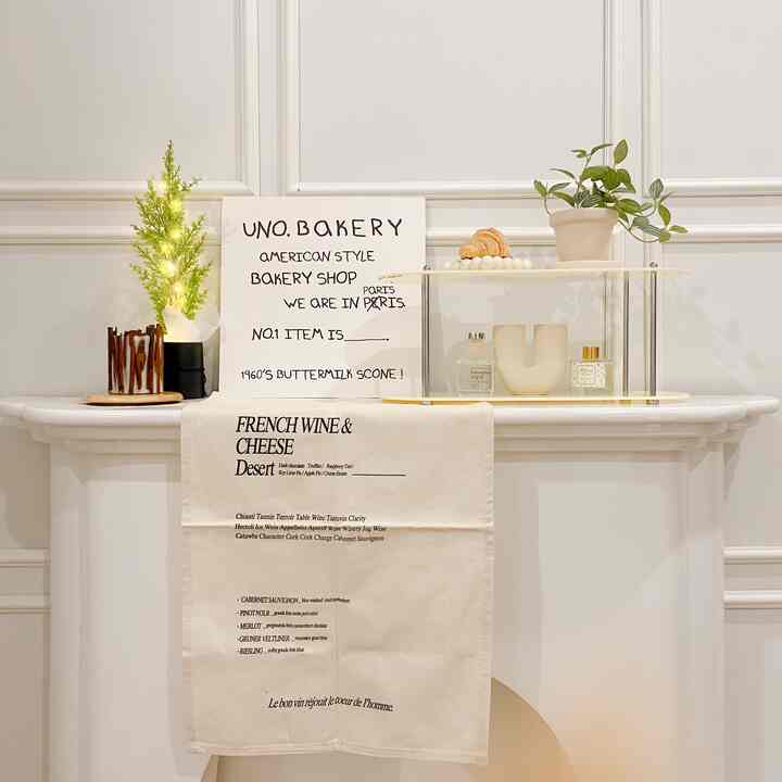 Ivory-toned living room with faux fireplace, featuring transparent acrylic shelf, plants, and a neatly arranged table runner