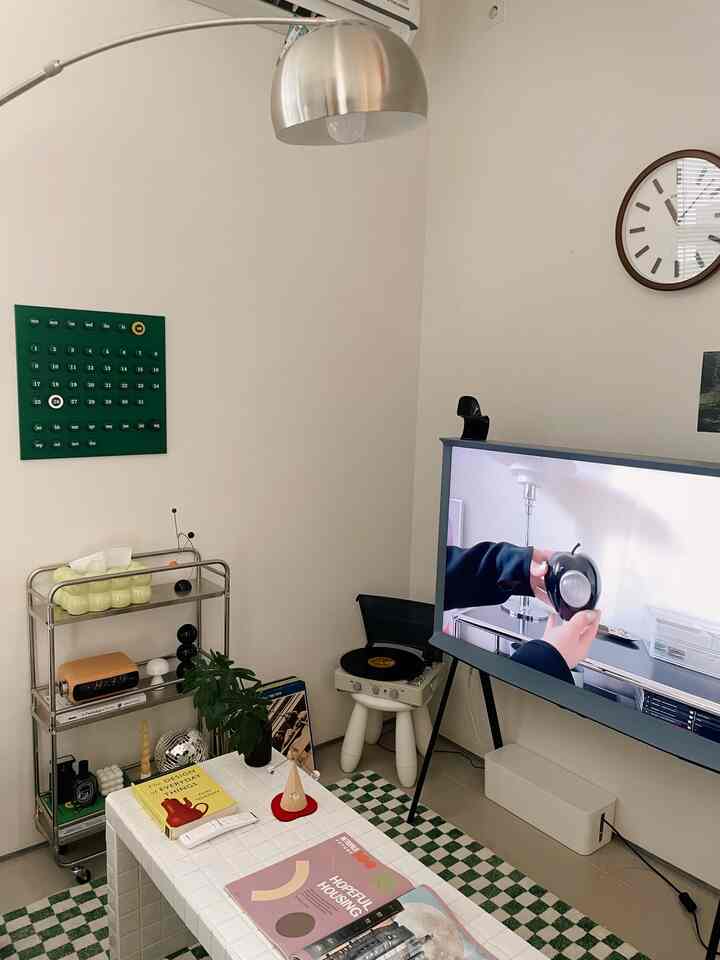 Monotone and green toned living room featuring TV stand and record player with mid-century modern decor