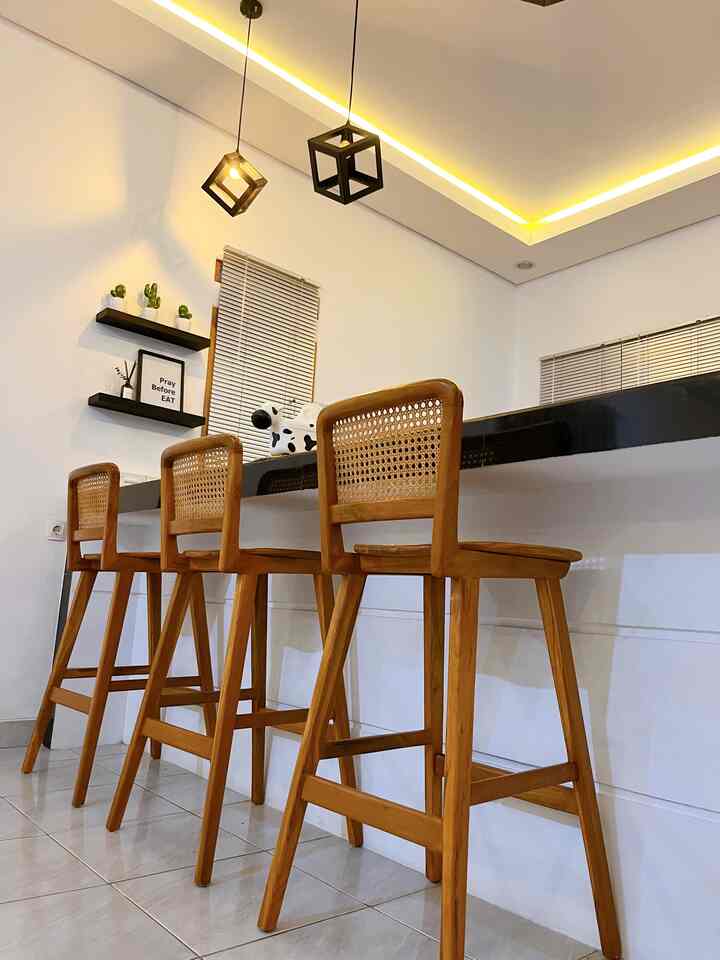 Monotone kitchen and dining space with white walls, black granite bar counter, and natural wood bar stools, featuring a simple and cafe-style interior