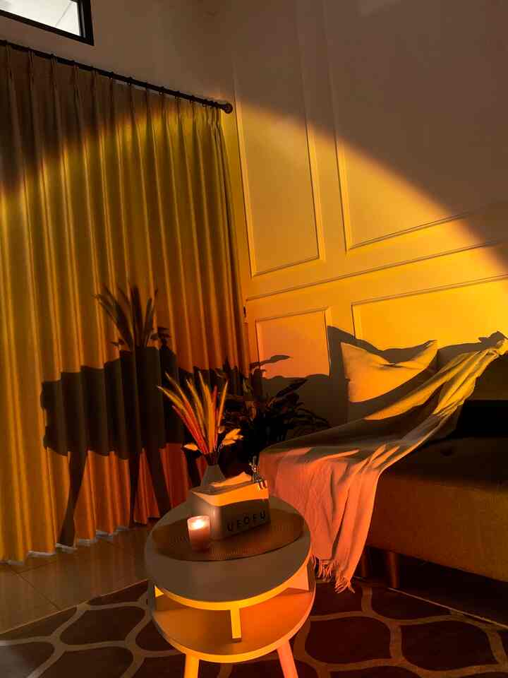 Warm orange-lit living room featuring sofa, coffee table, and dried flower decor creating a cozy atmosphere