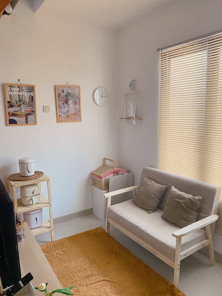 Bright white and wood tone living room featuring a sofa and blinds in a cozy compact space