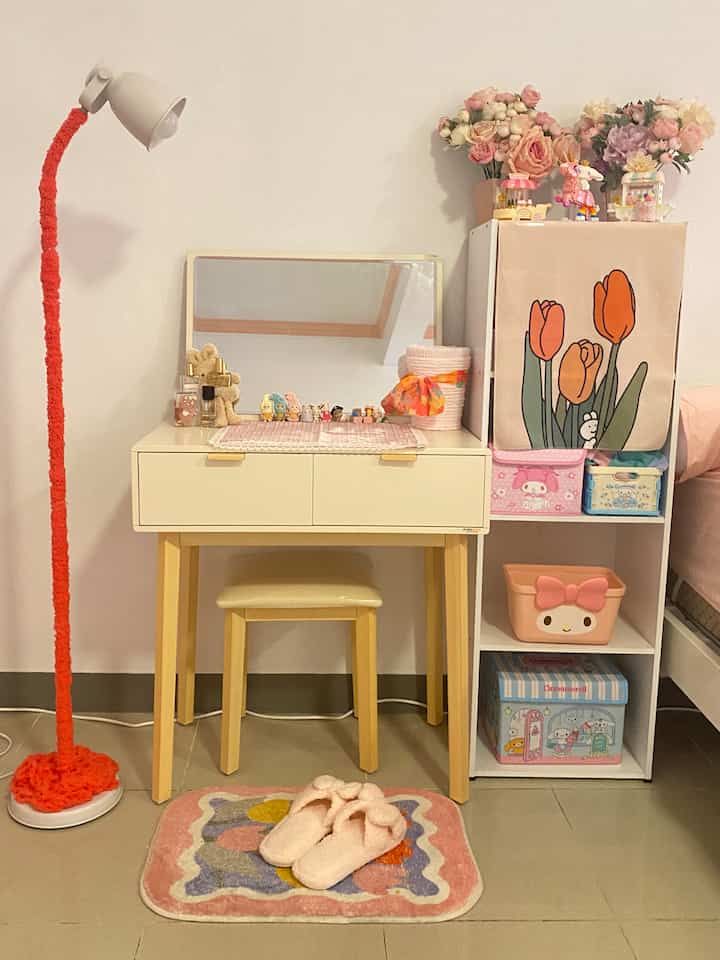 Ivory vanity desk with beige chair in a kids' room, decorated with pink accessories and vases for a cozy atmosphere