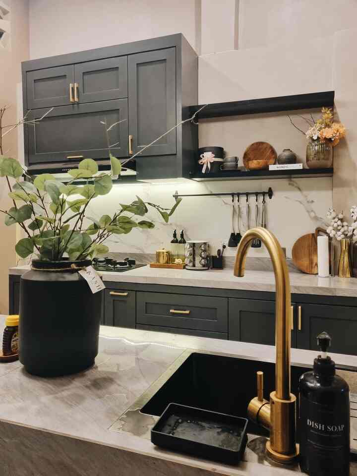 Modern kitchen in gray and gold tones with central plant and kitchen utensils, creating a stylish space