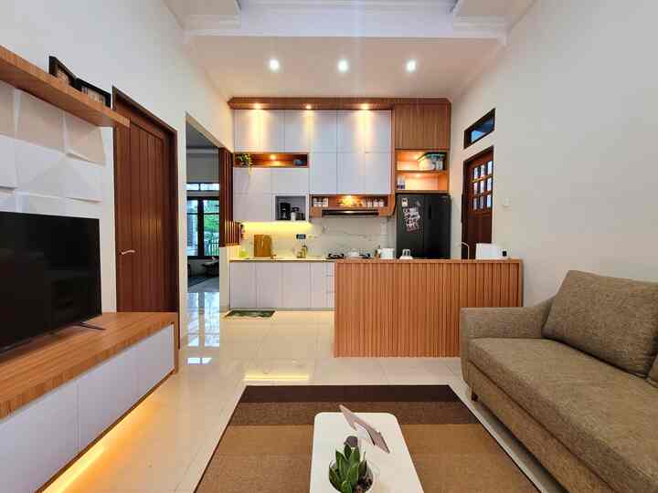A simple 4-person living space combining white and wood tone kitchen with living room
