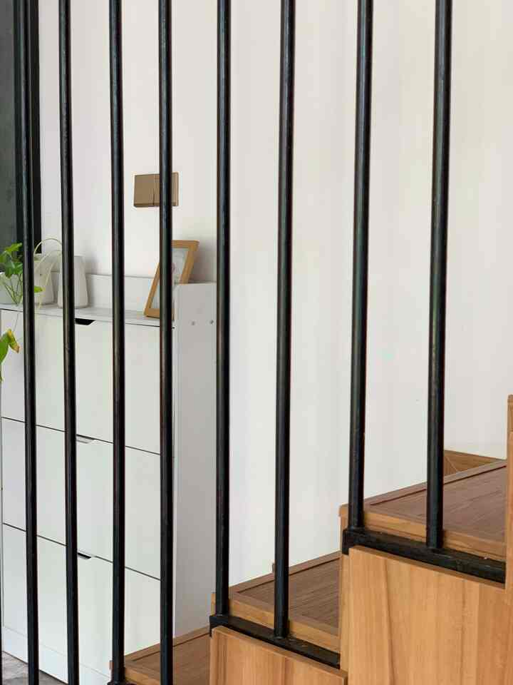 Compact space featuring stairs with natural wood tone and white storage cabinet against white walls