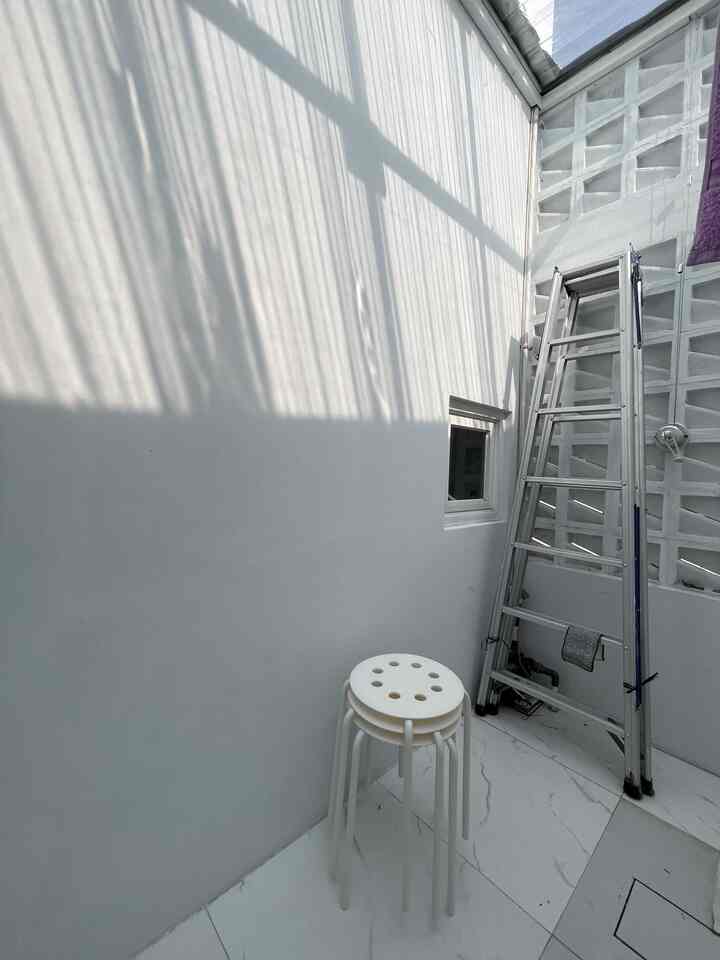 Bright white balcony space with transparent roof and roster wall, featuring neatly stacked stools and a ladder in a well-lit outdoor area