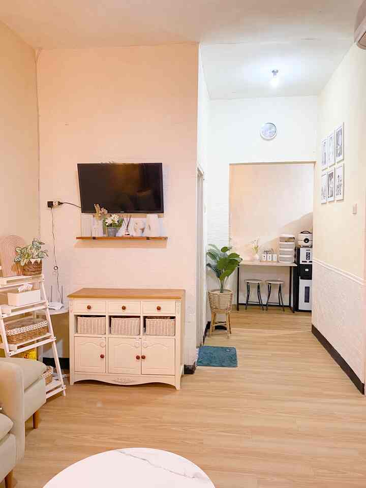 Natural wood tone flooring and light cream walls define a cozy 4.5-tatami living room featuring a sofa, wall-mounted TV, and dining chairs neatly arranged