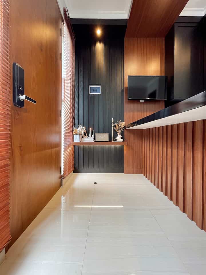 Dinding area foyer ditutup panel dengan aksen vertical, dan diberikan ambalan kayu sehingga saya bisa menambahkan hiasan dekorasi dried flowers, table lamp, maupun speaker untuk pelengkap TV. Supaya saat berkumpul kami bisa menonton TV, maka panel TV sengaja dibuat menyatu dan menerus ke panel ceiling meja.

Karena keterbatasan lahan, dan menyesuaikan dengan kebutuhan ruang sehingga dari awal saya memutuskan untuk membuat meja yang panjang secara custom, supaya kesan lebih lapang dan lebih banyak kegiatan bisa ditampung di meja ini. Untuk perkuatan bagian kaki meja juga diberi panel dengan aksen vertical senada dengan dinding foyer. 

#livingroomstyling
#livingroomdecor
#livingroommakeover
#homestyling
#warmcolor
#personalizedfurniture
#moderncontemporary