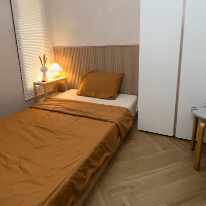 Simple kids' bedroom in warm brown and natural wood tones featuring a single bed and nightstand with cozy lighting