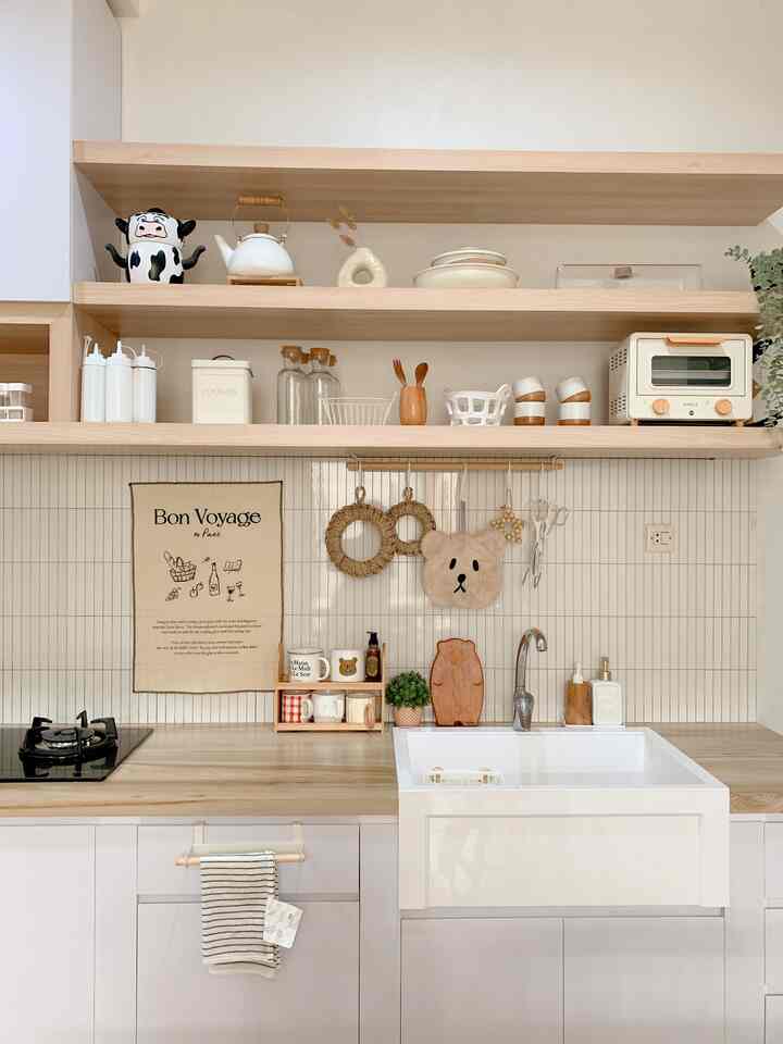 Bright kitchen in white and wood tones featuring sink, organized shelves, and cooking utensils with cozy, compact atmosphere