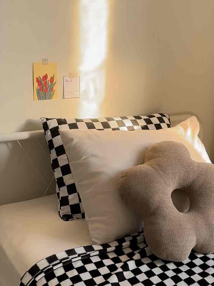 Beige-toned bedroom featuring checkered bedding and flower-shaped pillow with a cozy atmosphere