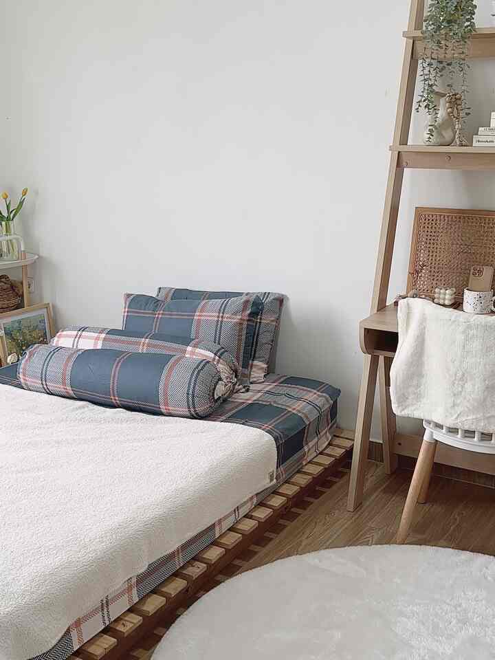 Natural color tones and wood elements define this compact bedroom featuring a wooden bed frame and desk for a cozy atmosphere