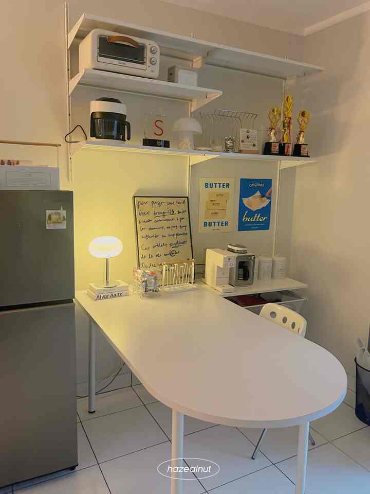 White-toned compact dining room featuring a custom half-circle dining table and coffee maker in a simple, minimalistic space
