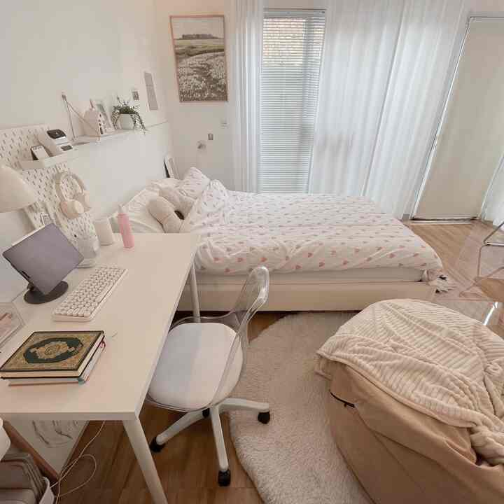 Warm natural-toned studio bedroom featuring a white desk and pink heart patterned bedding with cozy atmosphere