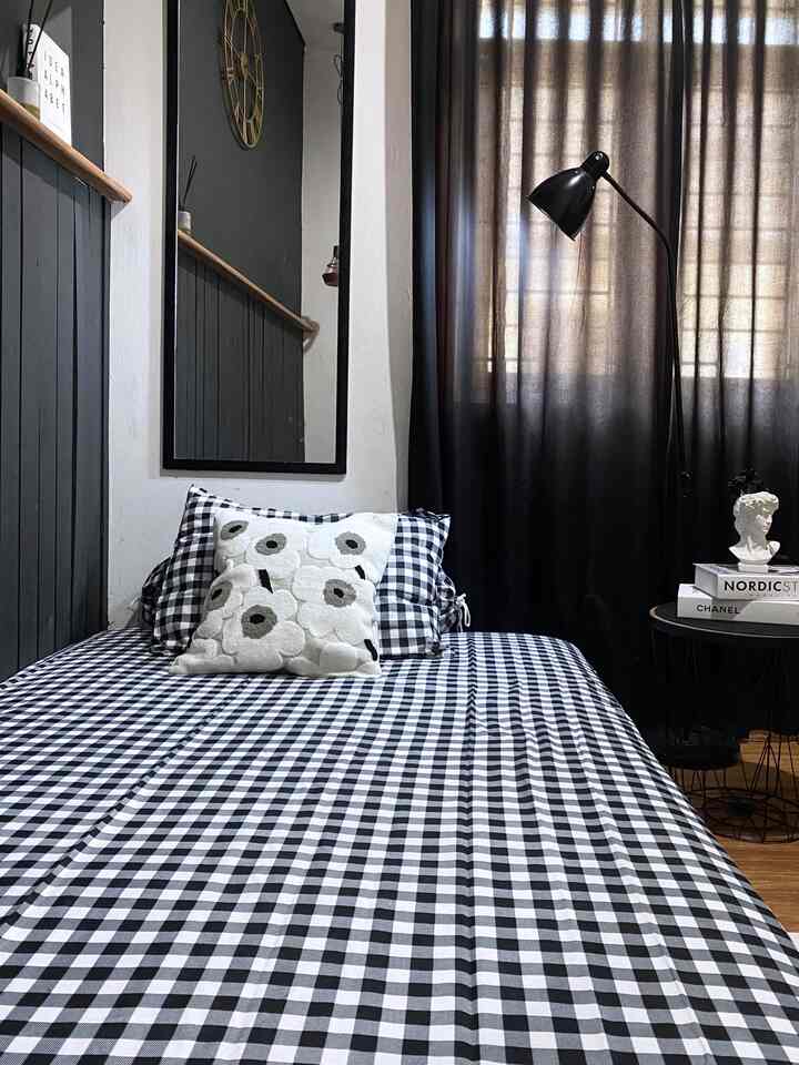 Monotone black and white bedroom featuring checkered bedding and blackout curtains in a minimalist setup