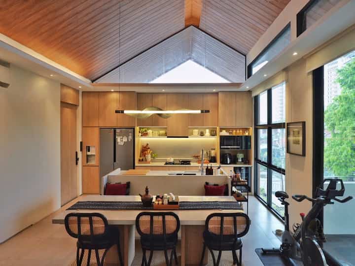 Natural wood tones and white colors define this dining room and kitchen with large windows and an open plan layout creating a spacious atmosphere