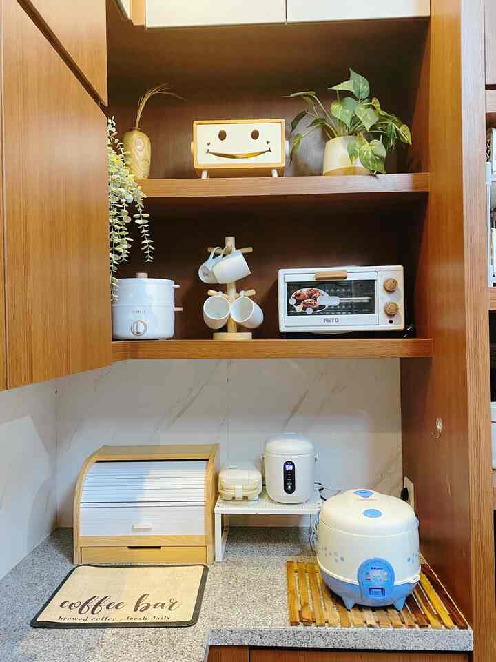 A compact 3x3m kitchen featuring dominant wood tones and white appliances, with efficient storage and various cooking devices arranged neatly