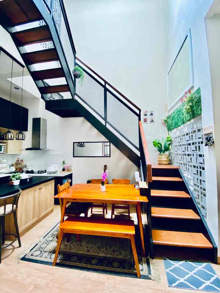 White walls and wood-tone dining table in an industrial style dining room featuring stairs and natural accents with a simple atmosphere