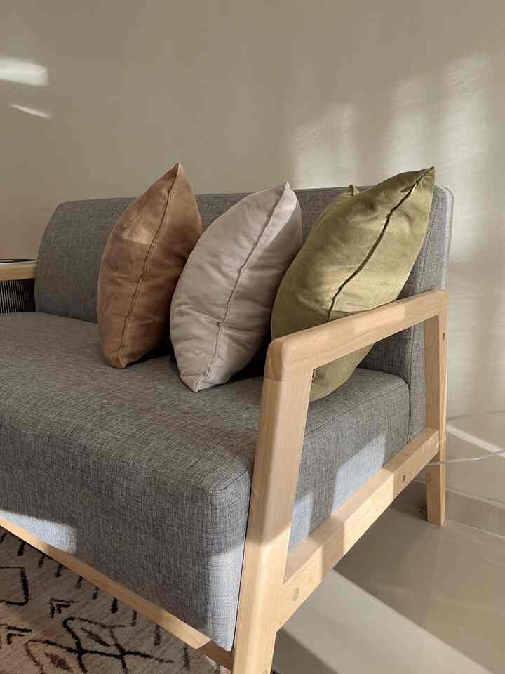 Natural tone living room featuring gray sofa with brown, beige, and olive cushions creating a warm atmosphere