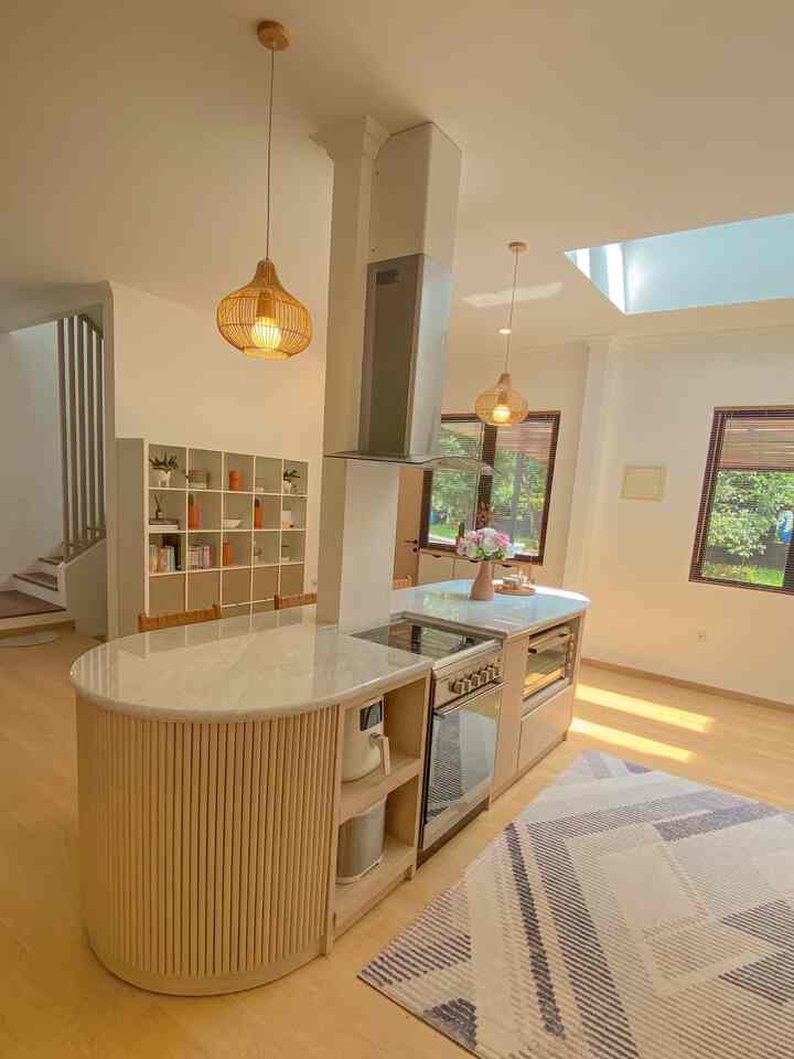 Bright white and wood-toned kitchen featuring a spacious layout with a central kitchen island and warm pendant lighting