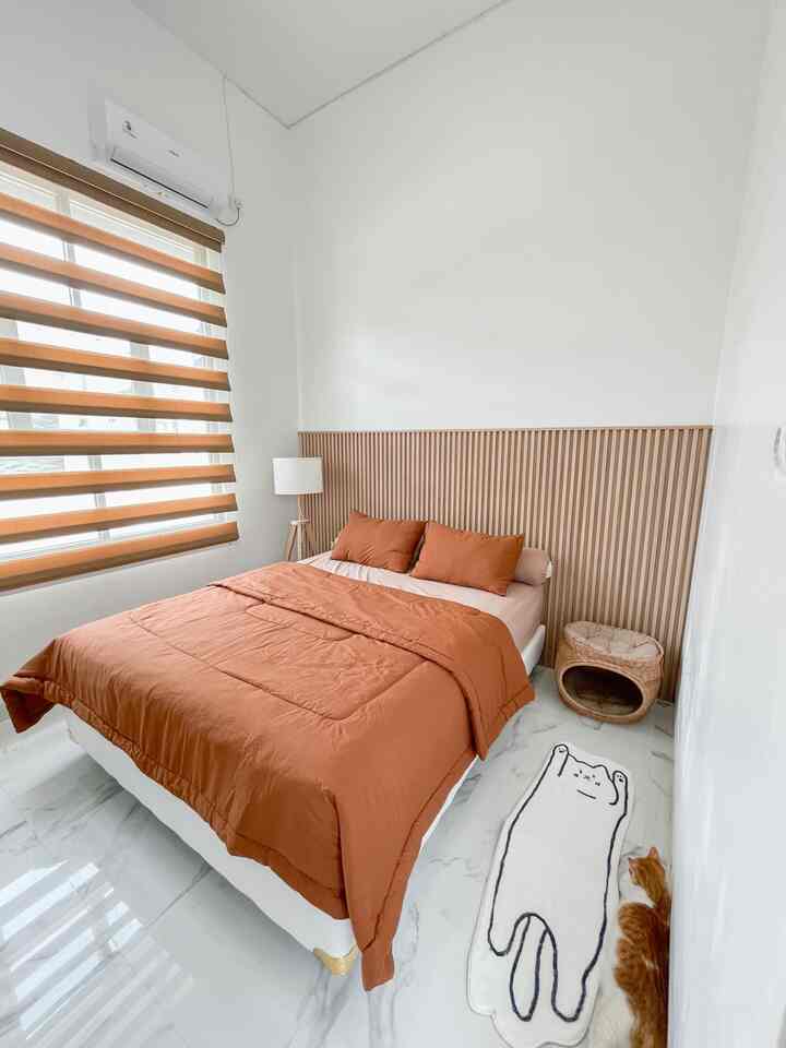 White and orange toned bedroom featuring orange bedding and a cat tower creating a cozy atmosphere