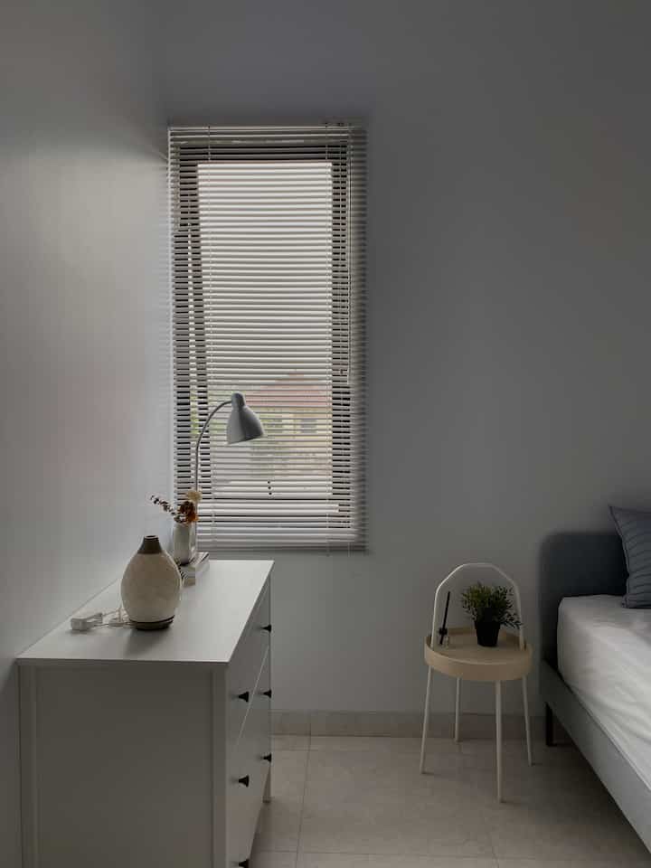 White and natural-toned bedroom featuring simple furniture layout with a cozy atmosphere