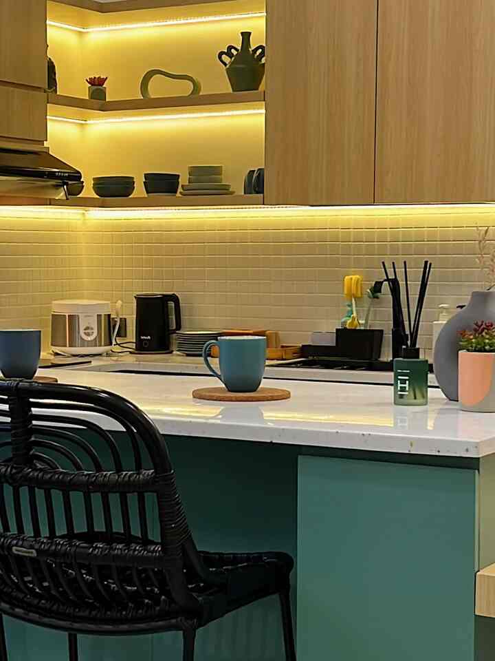 Warm wood tones and white tiles with blue accents in a kitchen and dining room space, accented by cozy LED ambient lighting