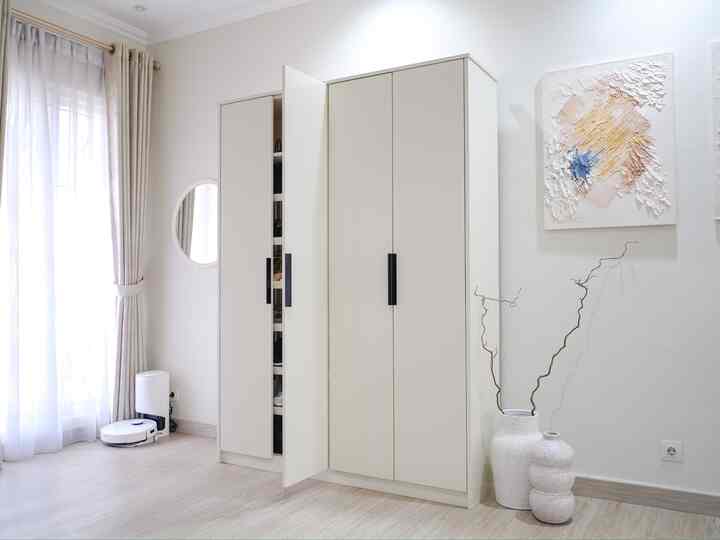 Natural color and white toned entrance space featuring large shoe cabinet, round mirror, and robot vacuum, creating a minimal and functional atmosphere