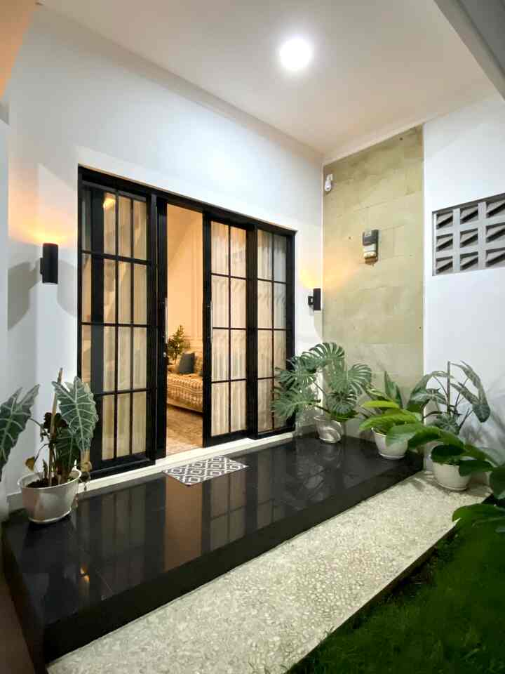 Suasana malam hari di teras bumi.kahiji. Teras ini menjadi salah satu spot favorit juga nih di bagian eksterior, karena banyak tanaman hijau yang bikin udara terasa segar dan sejuk saat pagi dan malam hari. 
Teras mini dengan lantai granit hitam dan pintu aluminium kaca besar yang membuat rumah ini memiliki ciri khas. 

#minimalist #rumahmungil #terasrumah #ekterior #bandung #terasmini #homedecor #rumahdikampung #rumahdesa