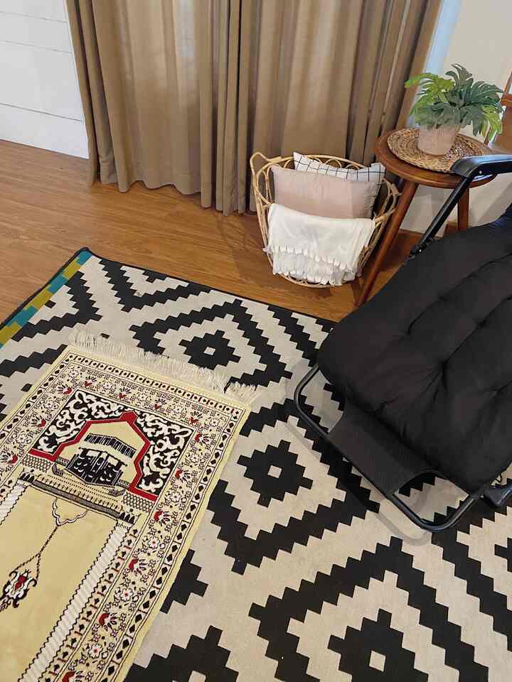 Brown and beige toned room featuring a black cushioned chair and patterned rug, creating a cozy natural interior space
