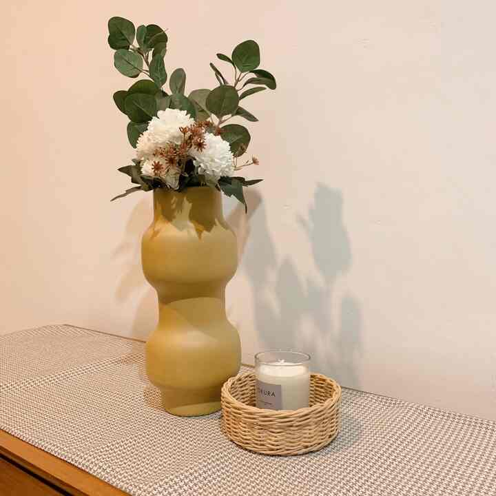 Natural brown-toned entrance space featuring an olive-colored vase and scented candle on a coco mocha table runner in a minimal interior