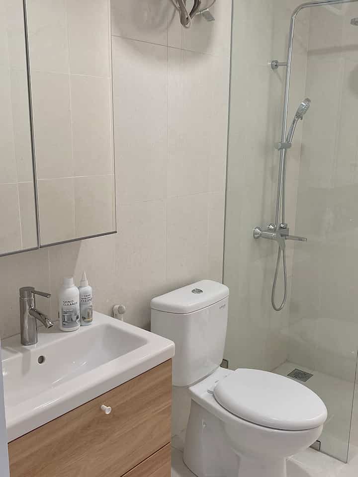 White and natural color bathroom featuring sink, toilet, and glass shower booth with a clean modern design