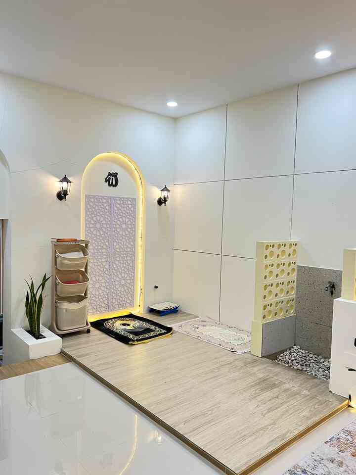 White and wood tone Muslim prayer space featuring prayer mats and lighting with a minimal interior