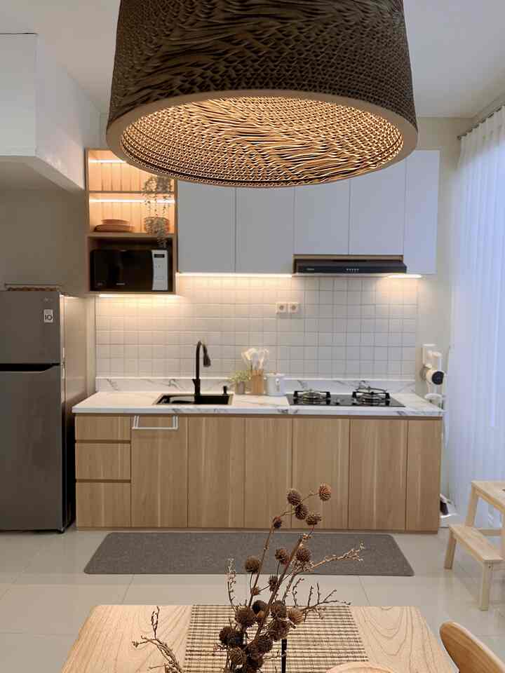 Warm wood tone kitchen featuring white cabinets, black faucet, and cozy pendant lighting centrally placed