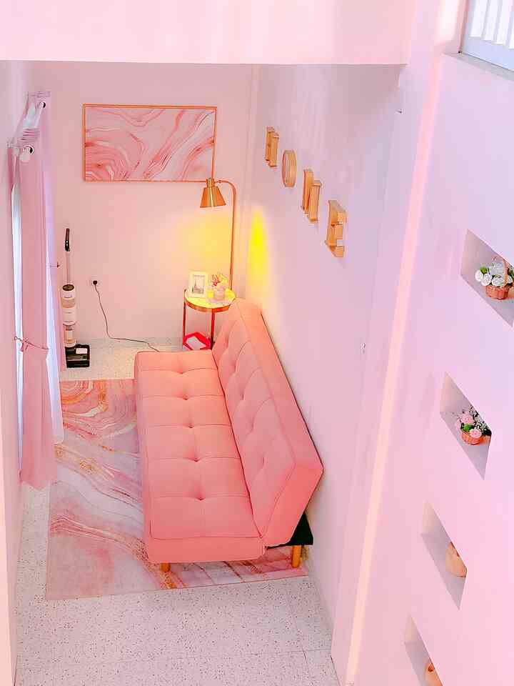 Pink-toned small living room featuring a sofa bed, side table, and gold accents creating a cozy atmosphere