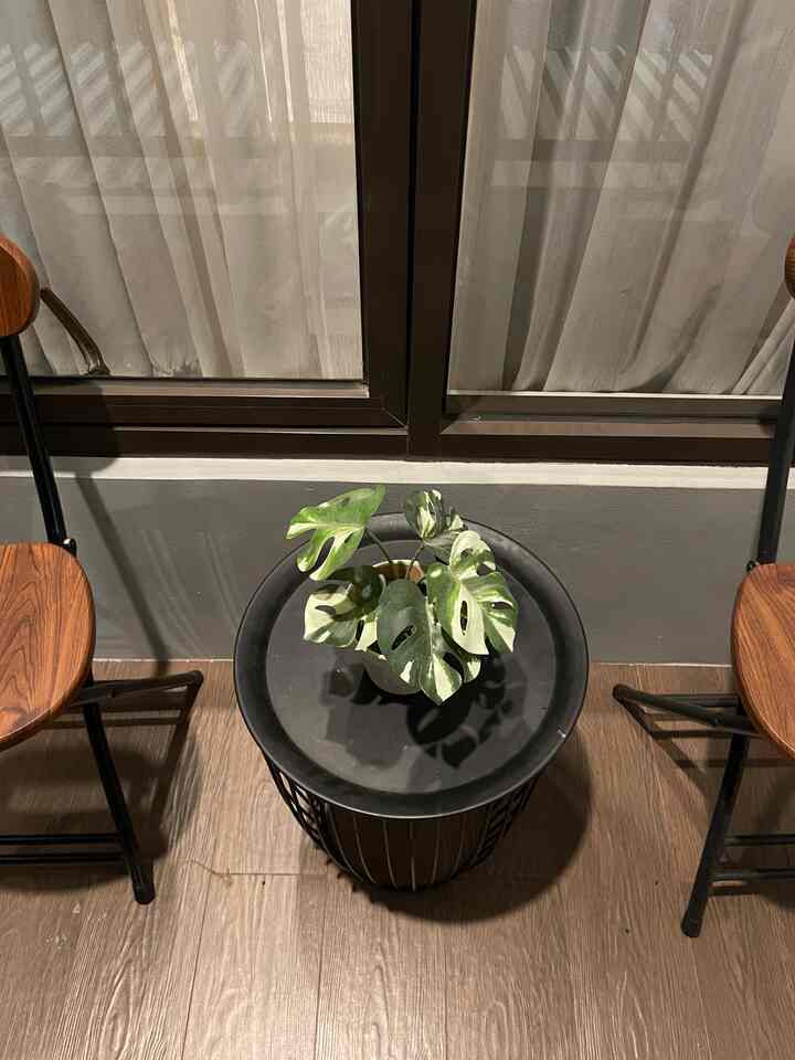 Wood tone flooring with black metal side table and armchairs arranged in a compact balcony space